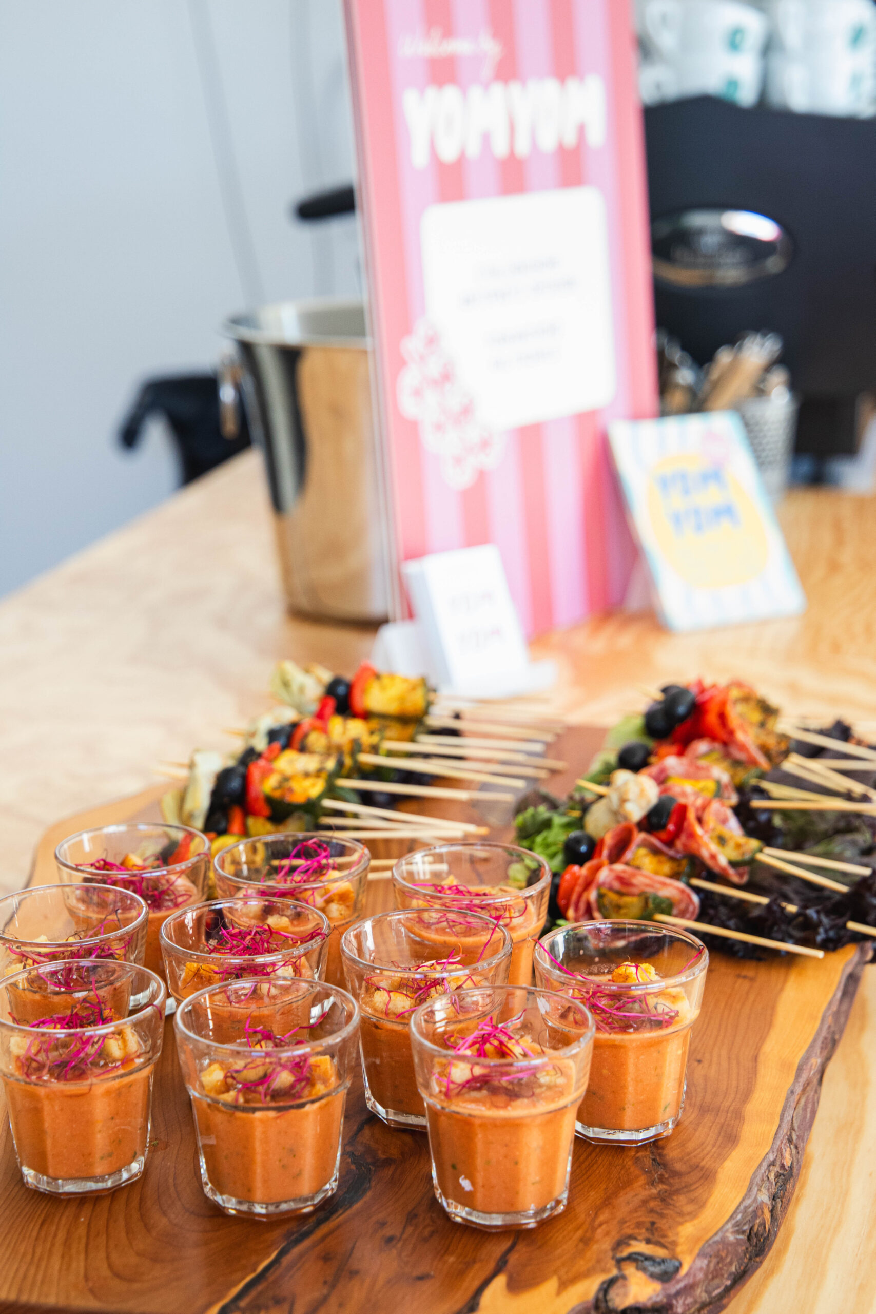 Gläser mit Gazpacho und Gemüsespiesse auf Holzplatte